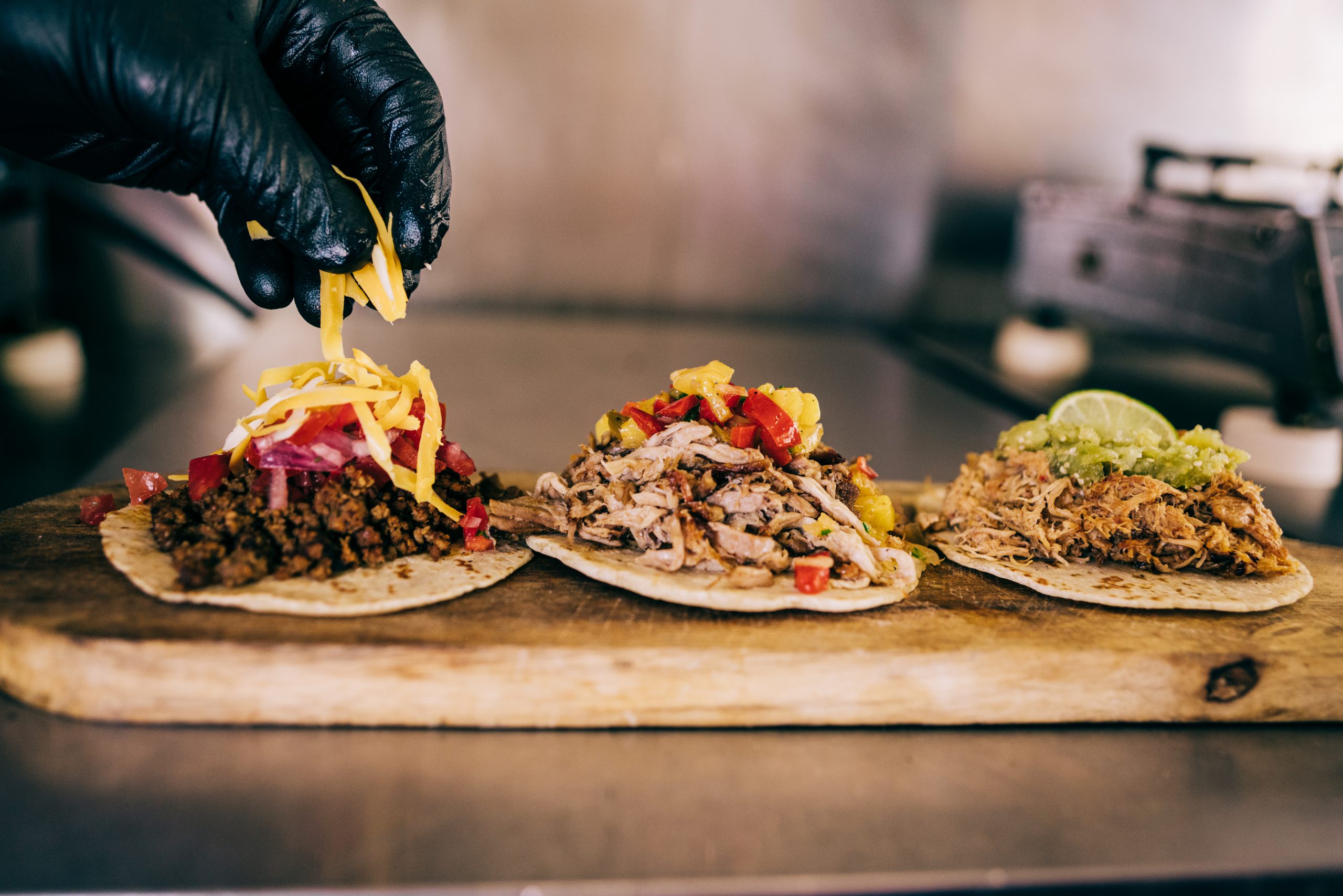 adding shredded cheese to street tacos