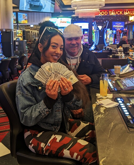 man and woman with cash jackpot at slot machine in legends bay casino