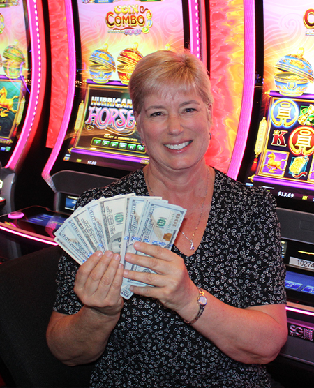 woman holding cash jackpot from slots at Legends Bay Casino
