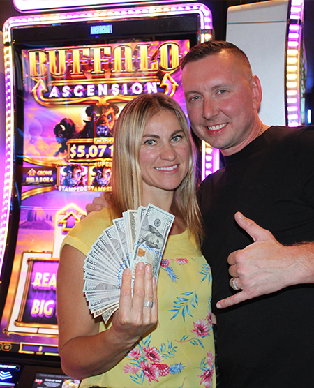 man and woman holding cash jackpot from slots at Legends Bay Casino