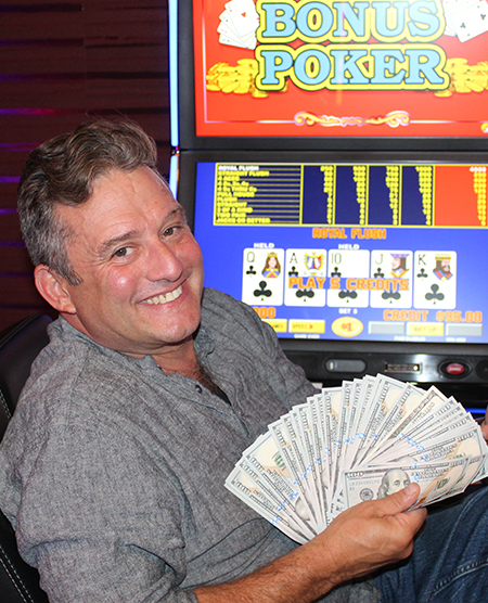 man holding cash jackpot from video poker at Legends Bay Casino