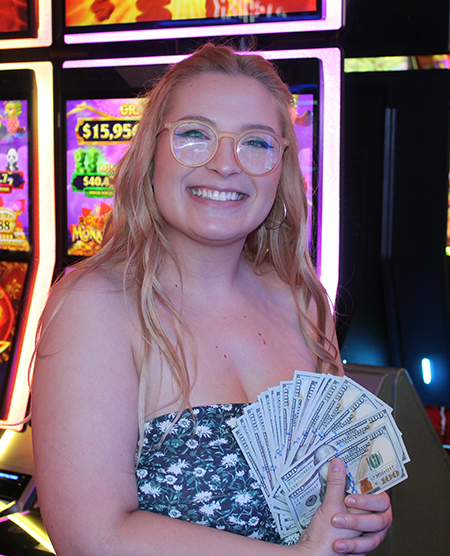 woman holding cash jackpot from slots at Legends Bay Casino