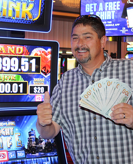 man holding cash jackpot from slots at Legends Bay Casino