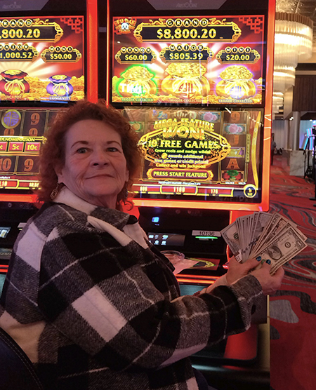 woman holding a slots jackpot at legends bay casino